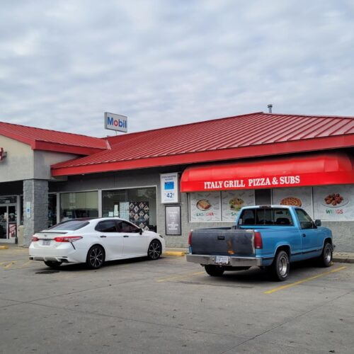 Exterior of a building with Italy Grill Pizza & Subs on the right-hand side and Dobb's Place on the left