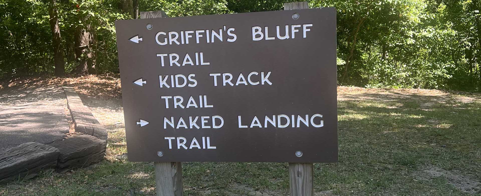 A trail sign at Princess Ann Access with the following: Griffin's Bluff Trail, Kids Track Trail, Naked Landing Trail. 