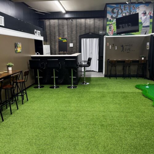 Interior of The Par Tees in Lumberton, NC with fake grass floor, high top bar, and suspended TVs