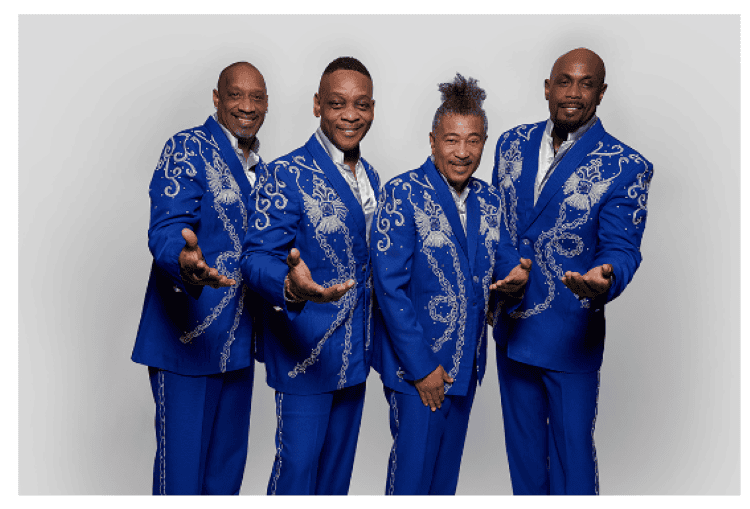 A group of men in a singing group all dressed in bright blue suits with their hands extended towards the viewer.